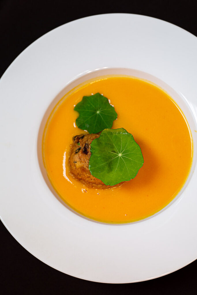 Soupe au butternut avec un beignet et une feuille verte